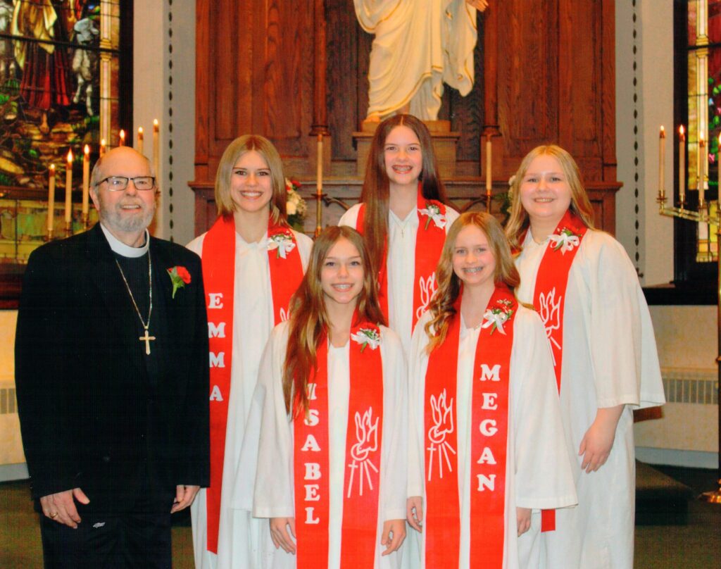 pastor with small group of students in their confirmation gowns