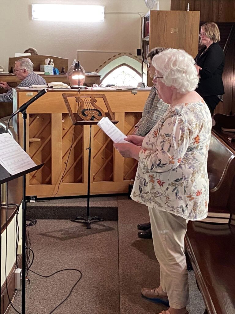 two women singing near a piano